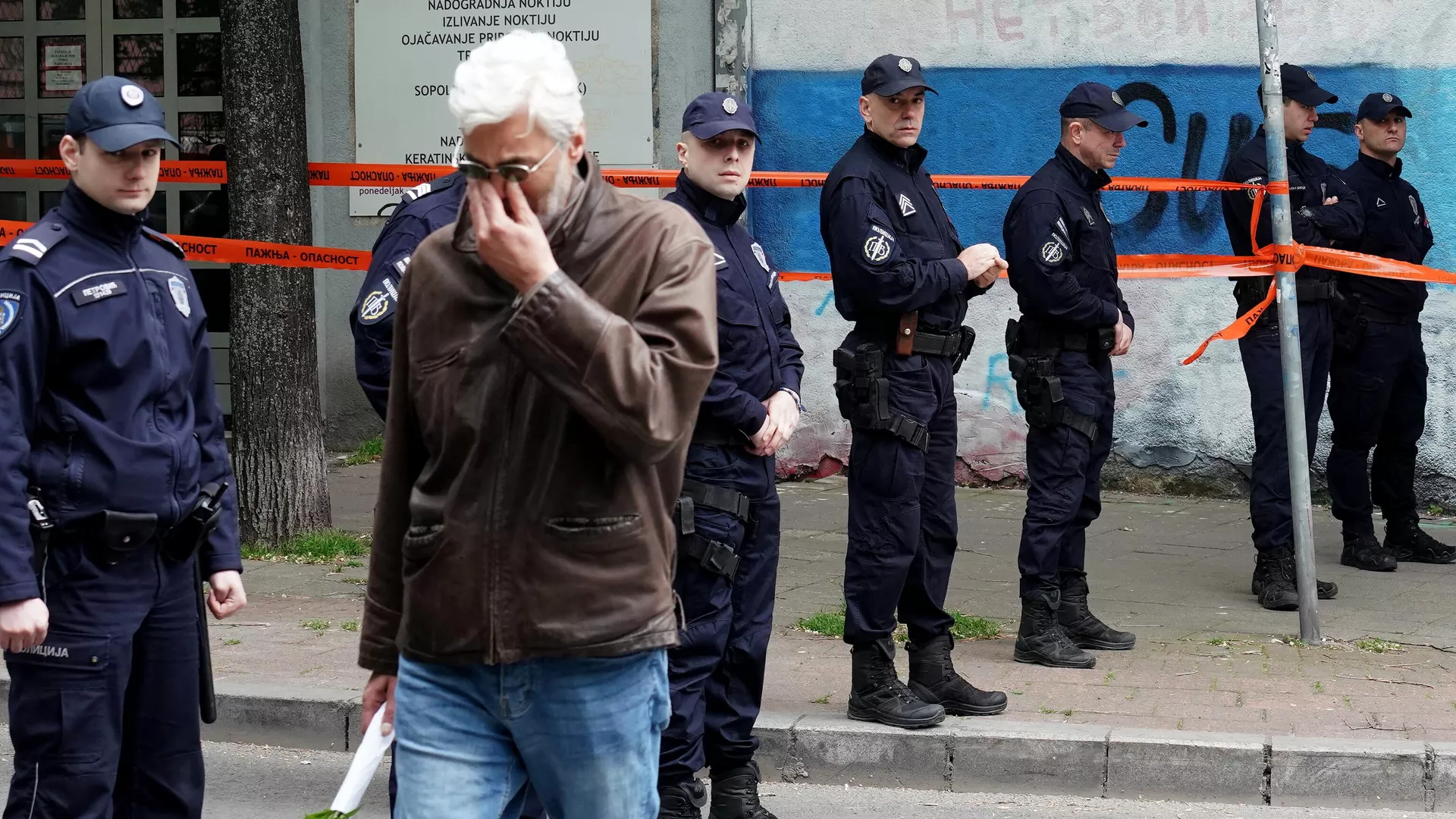 Un hombre llora mientras camina junto a los agentes de Policía que custodian la entrada de la escuela tras un tiroteo en una escuela de la capital, Belgrado, el 3 de mayo de 2023