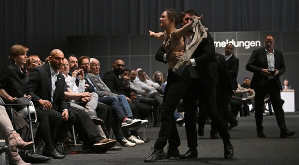 Guardias de seguridad escoltan a un activista que se opone a que Volkswagen lance autos con motores de combustión interna fuera de la asamblea general anual del consorcio automovilístico en Berlín, Alemania. - Sputnik Mundo