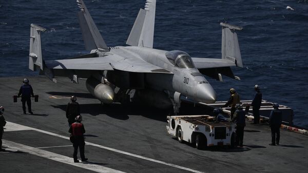 Un avión F-18 Super Hornet de la Marina de EEUU y sus tripulantes son vistos en la cubierta de vuelo del USS Nimitz, frente a la costa de Busan, el 27 de marzo de 2023.  - Sputnik Mundo