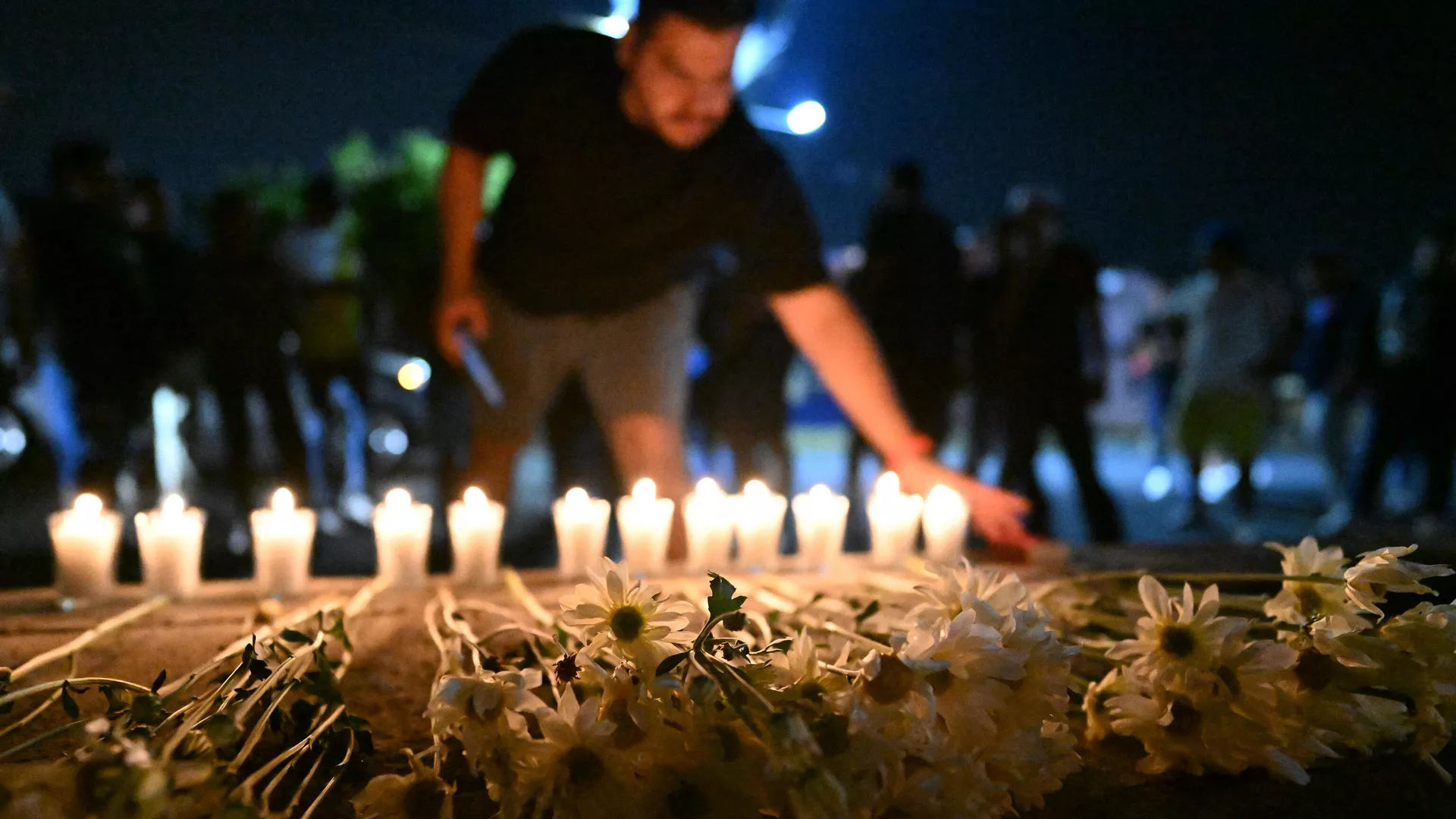 Simpatizantes de Alianza presentan sus respetos a las víctimas de una estampida en un monumento improvisado frente al estadio Cuscatlán de San Salvador.