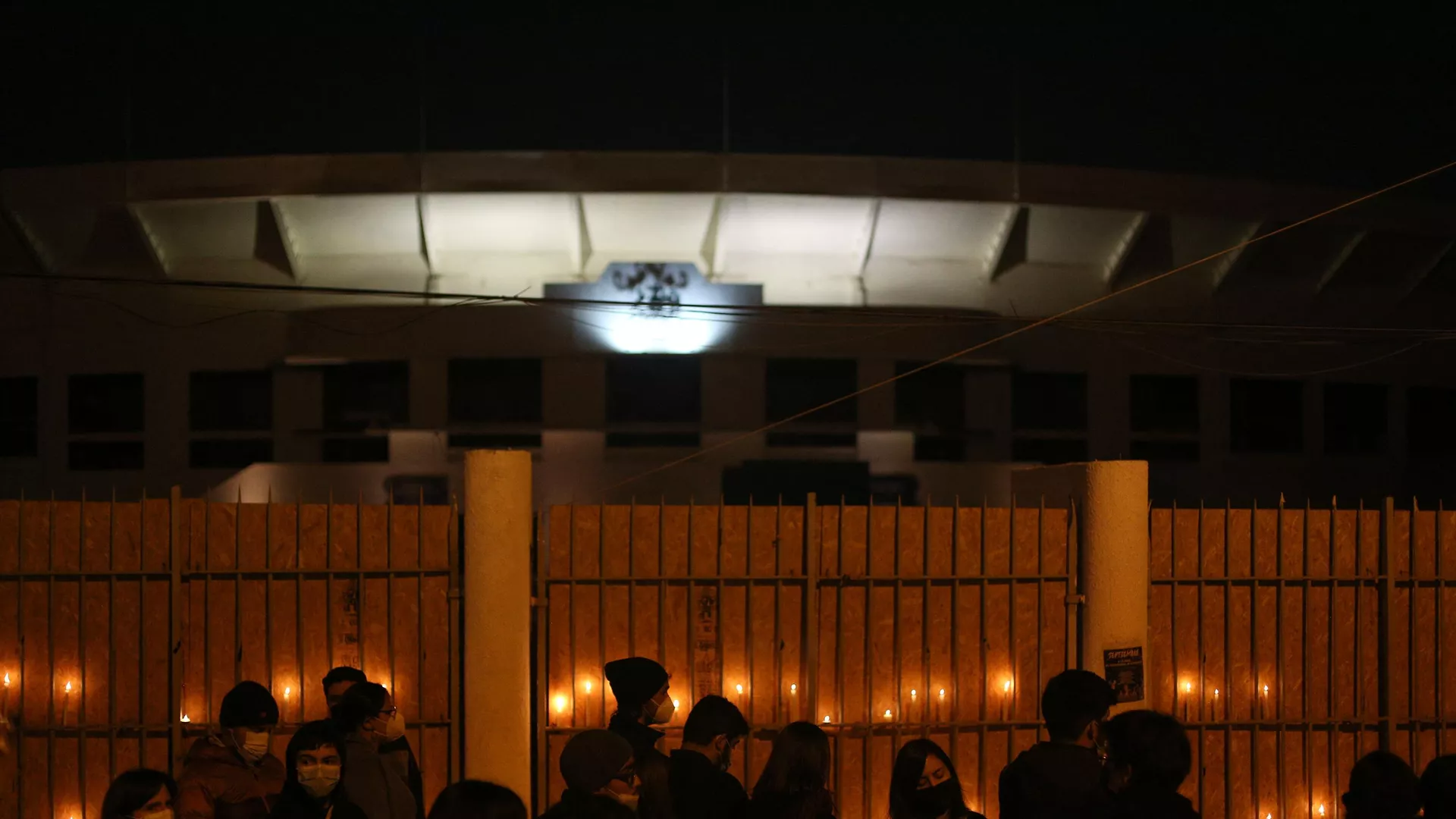Varias personas reunidas afuera del Estadio Nacional de Chile para prender veladoras en honor a las víctimas de tortura y detención de la dictadura militar de Augusto Pinochet (1973-1990).