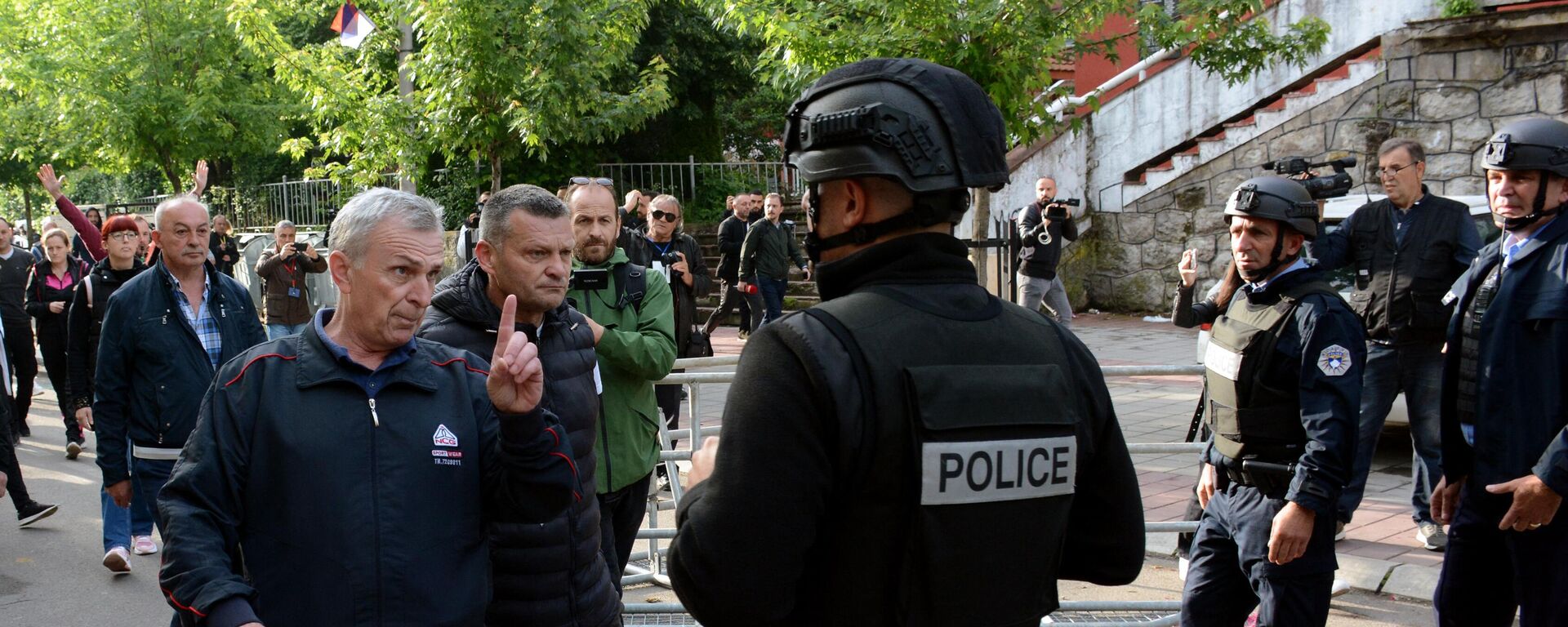 La Policía de Kosovo, junto con la Policía militar de la KFOR, aseguran el acceso a un edificio municipal en Zvecan mientras los serbokosovares se reúnen fuera del edificio, el 29 de mayo de 2023 - Sputnik Mundo, 1920, 29.05.2023