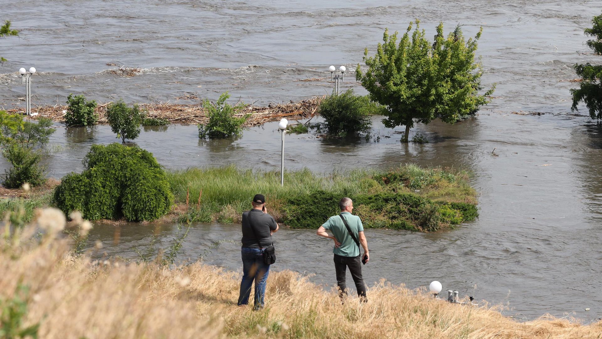 Residentes locales observan una zona parcialmente inundada de Jérson el 6 de junio de 2023, tras los daños sufridos en la presa de la central hidroeléctrica de Kajovka.   - Sputnik Mundo, 1920, 06.06.2023