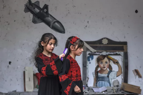 Los residentes de la ciudad de Deir al-Balah, en el centro de la Franja de Gaza, crearon murales y expusieron fragmentos de misiles israelíes para llamar la atención sobre la destrucción de sus hogares y la muerte de civiles.En la foto: Niñas palestinas delante de un mural en la pared de una de las casas destruidas de la comunidad. Los residentes de la ciudad de Deir al-Balah, en el centro de la Franja de Gaza, crearon murales y expusieron fragmentos de misiles israelíes para llamar la atención sobre la destrucción de sus hogares y la muerte de civiles.En la foto: Niñas palestinas delante de un mural en la pared de una de las casas destruidas de la comunidad. - Sputnik Mundo