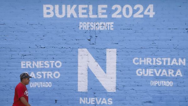 Un residente pasa junto a un cartel electoral del partido Nuevas Ideas que promueve la reelección del presidenteб Nayib Bukeleб en Soyapango - Sputnik Mundo