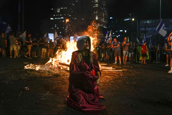 Un manifestante vestido como un personaje de la serie de televisión El cuento de la criada bloquea una autopista en la capital israelí, Tel Aviv. Miles de judíos salieron a la calle y bloquearon varias autopistas importantes en todo el país para protestar contra la reforma judicial. - Sputnik Mundo