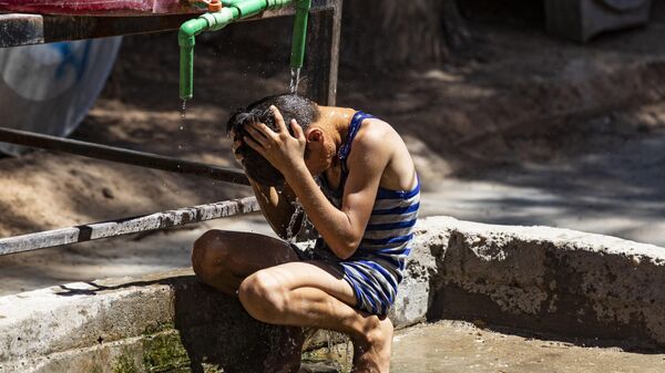 Un niño se refresca bajo el agua cuando hace calor en Siria - Sputnik Mundo