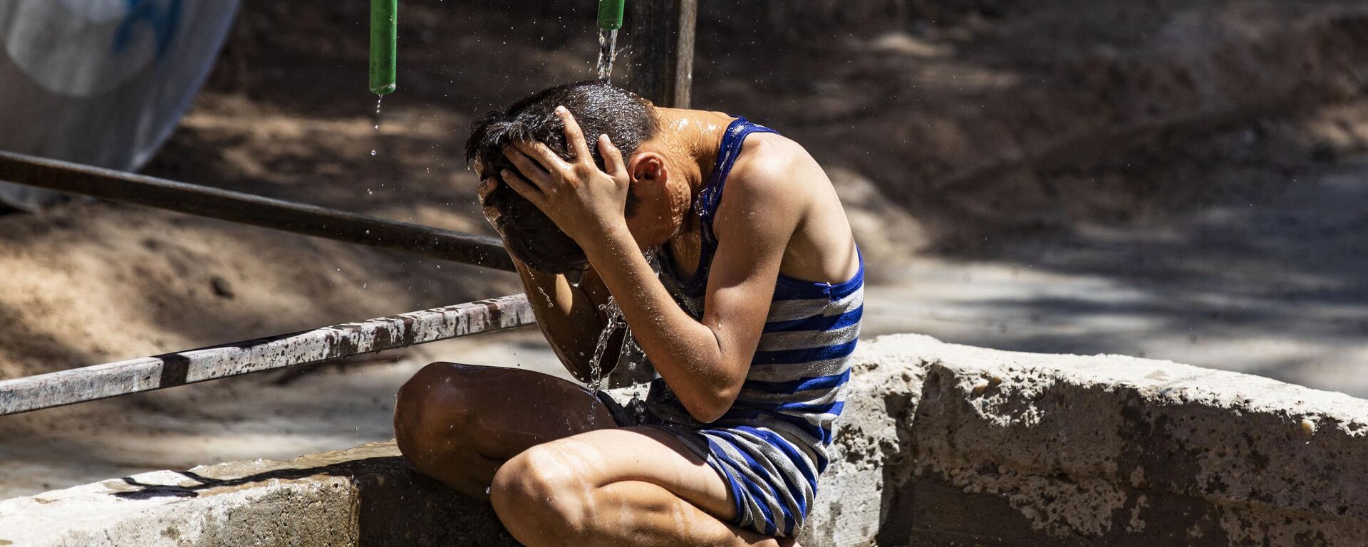 Un niño se refresca bajo el agua cuando hace calor en Siria - Sputnik Mundo, 1920, 24.07.2023