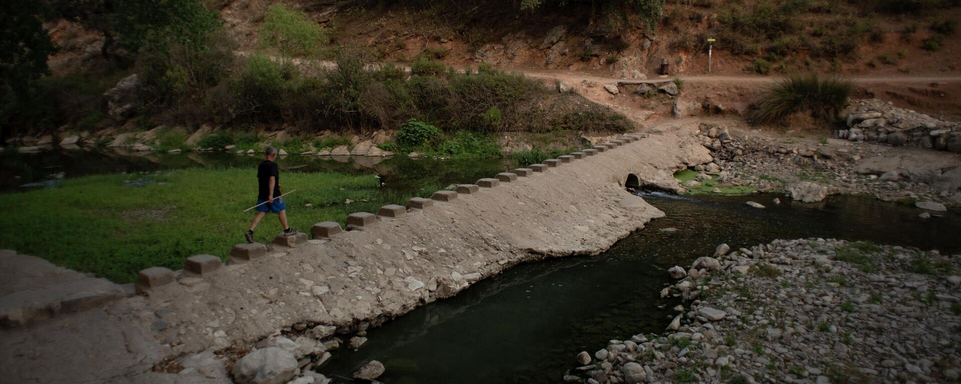 Un hombre pasa junto a una presa de agua en el río Guadiaro en Benaoján, España, el 20 de julio de 2023 - Sputnik Mundo, 1920, 04.08.2023