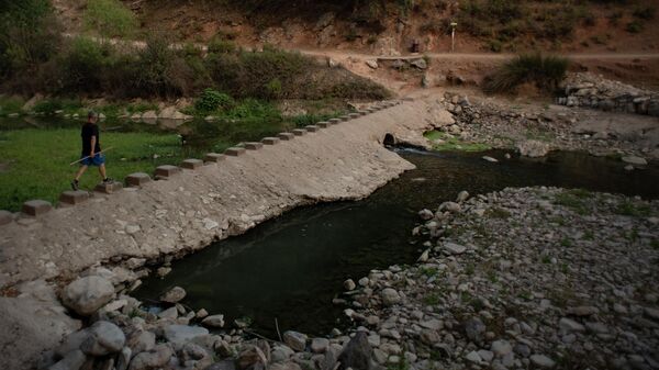 Un hombre pasa junto a una presa de agua en el río Guadiaro en Benaoján, España, el 20 de julio de 2023 - Sputnik Mundo