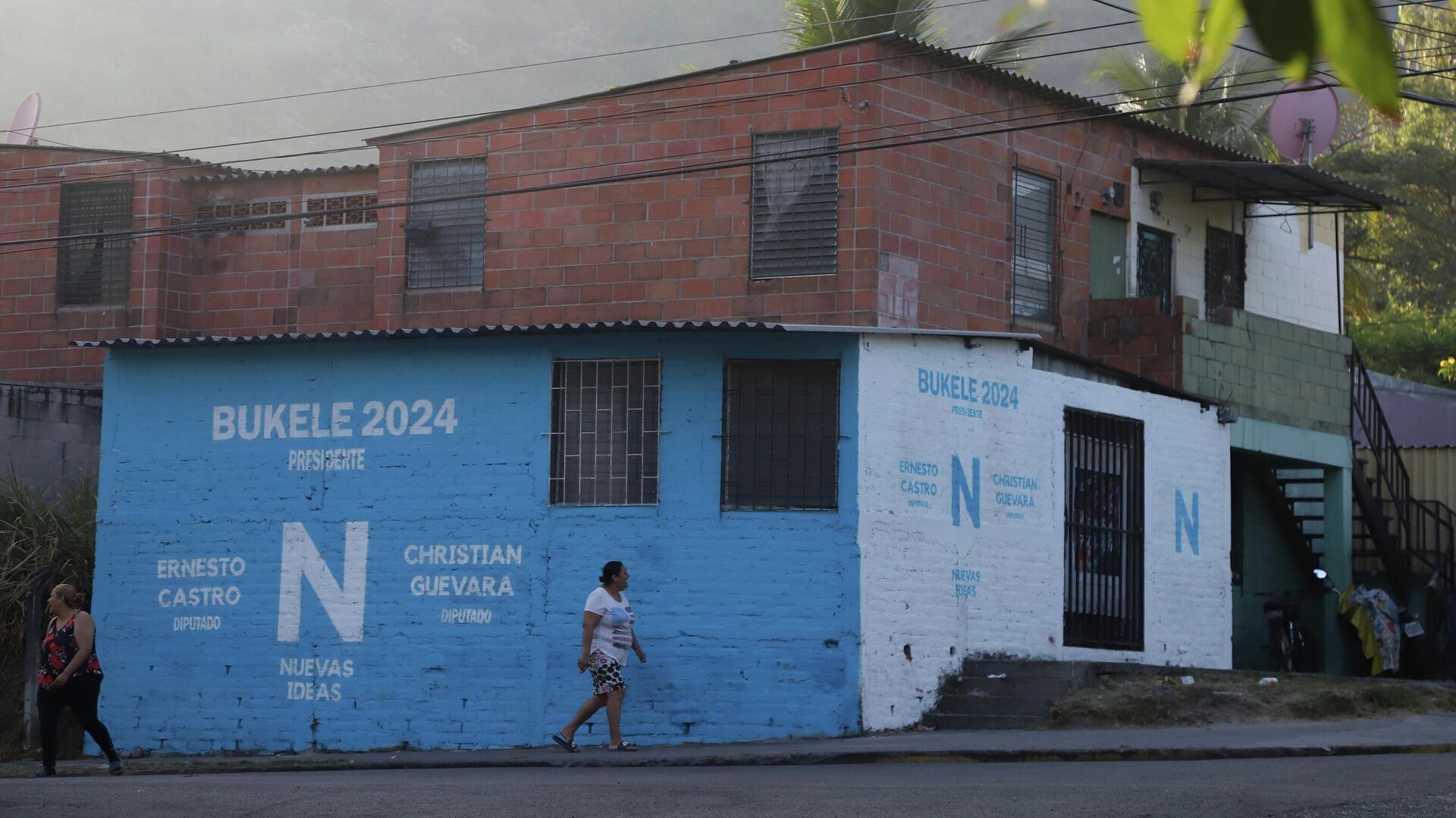Varios residentes pasan junto a un cartel del partido Nuevas Ideas, que hace campaña por la reelección del presidente Nayib Bukele, en Soyapango, El Salvador Varios residentes pasan junto a un cartel del partido Nuevas Ideas, que hace campaña por la reelección del presidente Nayib Bukele, en Soyapango, El Salvador - Sputnik Mundo, 1920, 07.08.2023