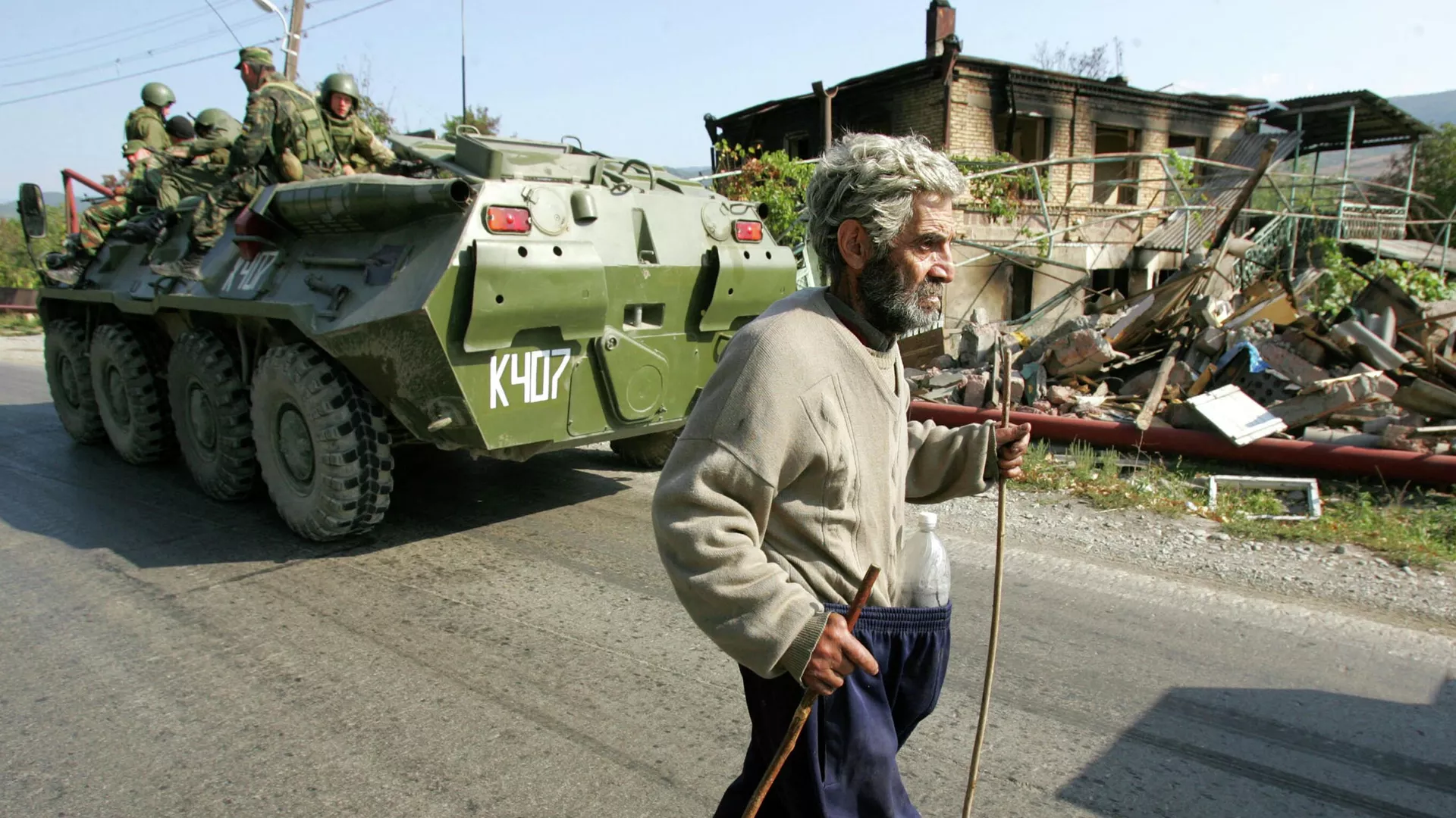 El residente pasa junto a tropas rusas en un vehículo blindado de transporte de tropas y edificios destruidos en Kurta, 20 kms al norte de Tsjinvali, Osetia del Sur, el 5 de septiembre de 2008.