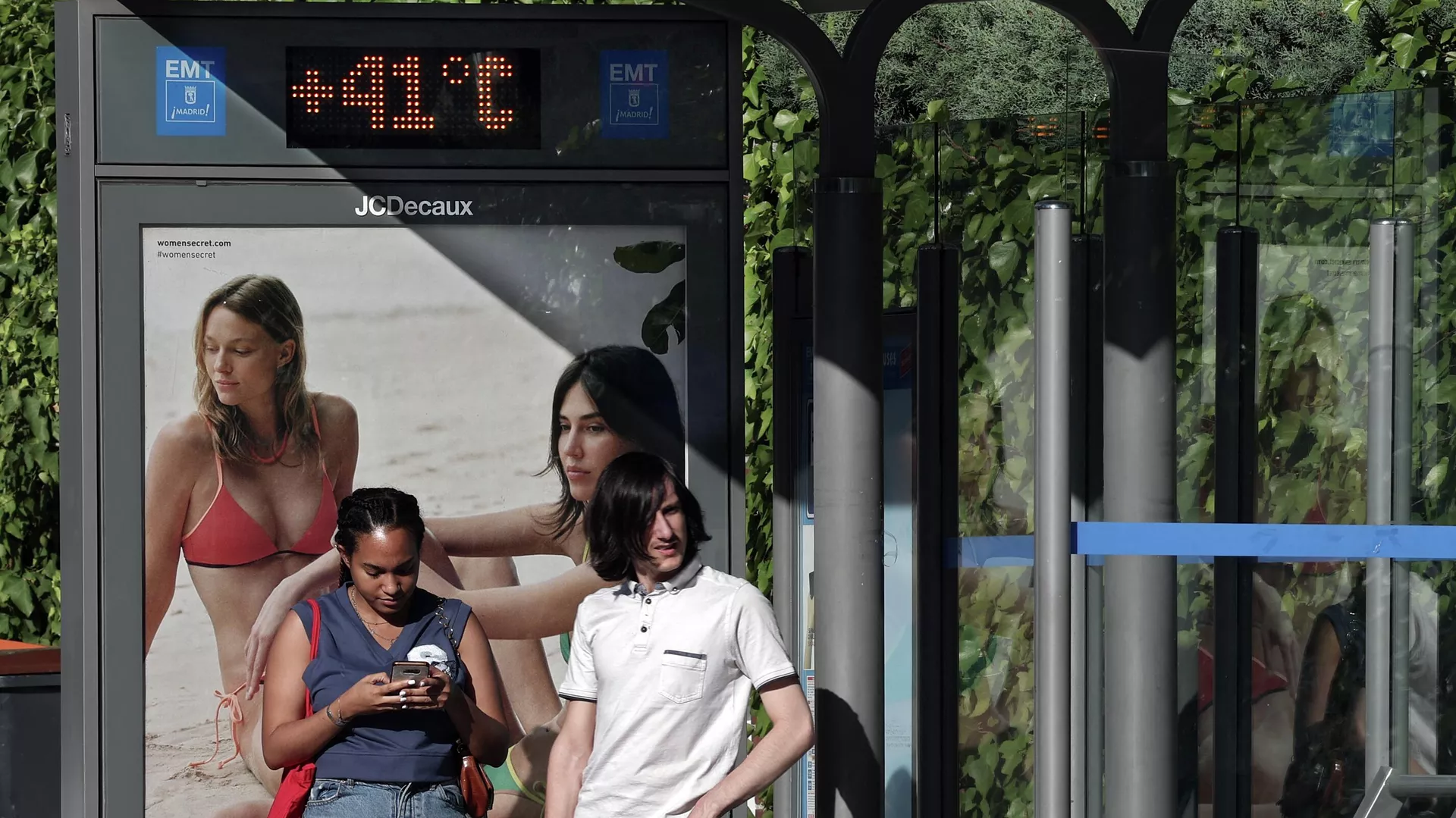 Personas esperan el autobús en una parada con un termómetro que marca 41 grados centígrados en Madrid, el 7 de julio de 2023 