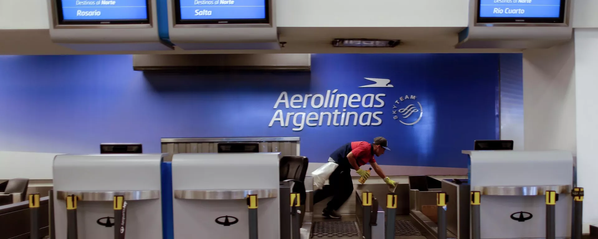 Un trabajador limpia el mostrador de facturación de Aerolíneas Argentinas en el aeropuerto de Buenos Aires, Argentina - Sputnik Mundo, 1920, 04.01.2025