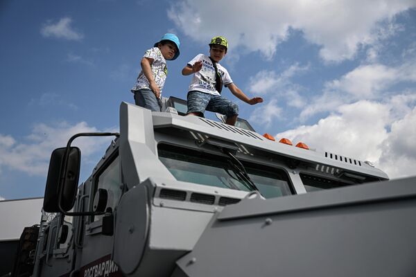 Niños en el techo del vehículo blindado polivalente Spartak. La parte frontal y los laterales del vehículo, incluidas las ventanillas, pueden resistir balas incendiarias perforantes, mientras que la parte inferior protege a la tripulación de la detonación de artefactos explosivos bajo las ruedas de hasta 6 kg de equivalente en TNT. - Sputnik Mundo