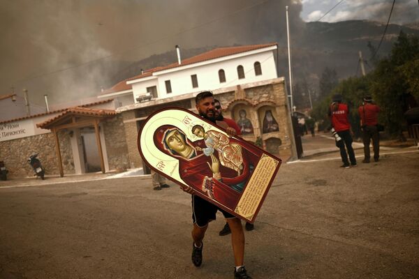 Un voluntario lleva un icono rescatado de un monasterio en llamas en Acharnes, Grecia, afectada por un incendio forestal. Un voluntario lleva un icono rescatado de un monasterio en llamas en Acharnes, Grecia, afectada por un incendio forestal. - Sputnik Mundo