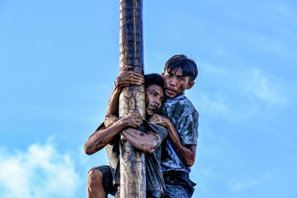 Durante las celebraciones del Día de la Independencia de Indonesia en Banda Aceh, los participantes trepan por el Panjat Pinang, un poste untado con aceite, para recoger los premios suspendidos en su cima. Durante las celebraciones del Día de la Independencia de Indonesia en Banda Aceh, los participantes trepan por el Panjat Pinang, un poste untado con aceite, para recoger los premios suspendidos en su cima. - Sputnik Mundo