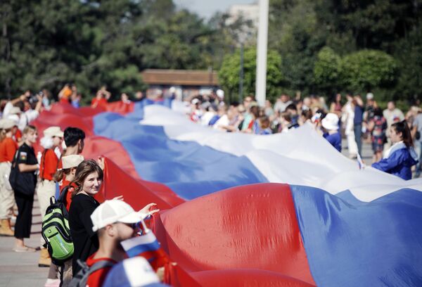 Personas despliegan una bandera rusa de 100 metros en la ciudad de Mariúpol en las celebraciones por el Día de la Bandera de Rusia. Personas despliegan una bandera rusa de 100 metros en la ciudad de Mariúpol en las celebraciones por el Día de la Bandera de Rusia. - Sputnik Mundo