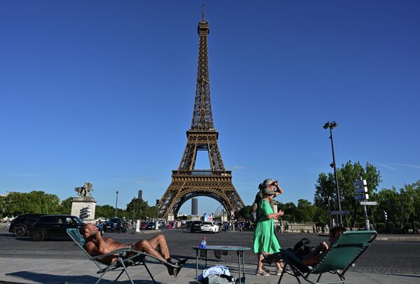 Personas frente a la Torre Eiffel en París. En 49 departamentos de Francia, anunciaron el nivel naranja de peligro climático por un calor anómalo. Personas frente a la Torre Eiffel en París. En 49 departamentos de Francia, anunciaron el nivel naranja de peligro climático por un calor anómalo. - Sputnik Mundo