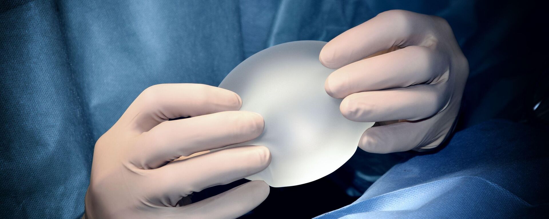 Un cirujano con un implante mamario en las manos durante una cirugía estética - Sputnik Mundo, 1920, 02.09.2023