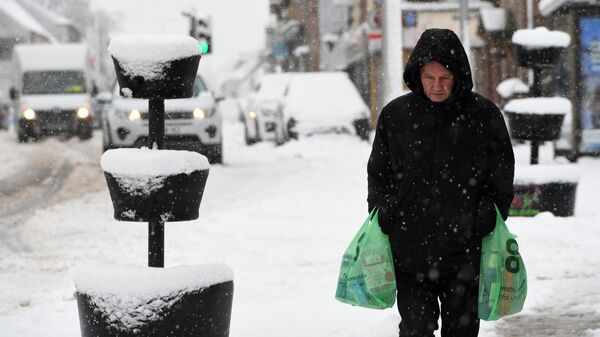 Un hombre lleva sus compras a través de la nieve en Escocia, el 18 de febrero de 2022  - Sputnik Mundo