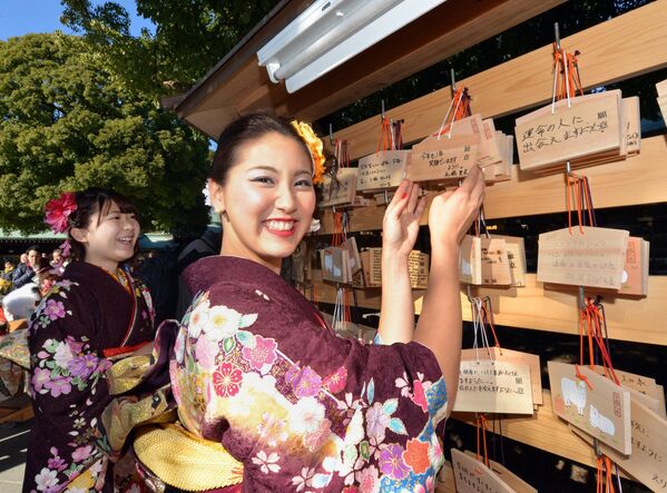 Guías turísticas de 20 años vestidas con kimonos tradicionales cuelgan emas, o tablillas votivas con sus deseos escritos en el Santuario Meiji de Tokio tras asistir a una ceremonia de purificación con un sacerdote sintoísta para celebrar el Día de la Mayoría de Edad en Japón el 9 de enero de 2015. Los jóvenes que cumplen 20 años son reconocidos oficialmente como adultos en Japón. - Sputnik Mundo