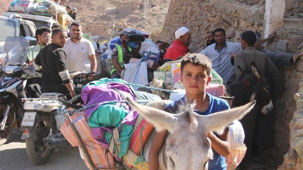 Adultos y niños participan en el reparto de ayuda en las montañas afectadas por el terremoto de Marruecos, 15 de septiembre de 2023 - Sputnik Mundo