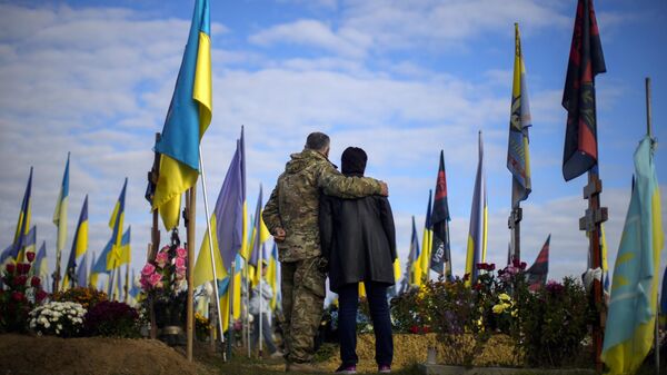 Los padres de un soldado ucraniano en un cementerio durante el Día de los Defensores de Ucrania en Járkov, Ucrania, el 14 de octubre de 2022  - Sputnik Mundo