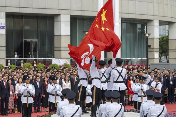 Durante el periodo de celebración, enormes banderas nacionales y retratos de líderes populares cuelgan por todas partes en China, incluida la imagen de Mao Zedong, fundador de la República Popular China. Las calles de Pekín y otras ciudades chinas se decoran con enormes arreglos florales y estilizados carteles, figuras de elefantes y dragones, que simbolizan la abundancia, la prosperidad y el crecimiento personal. En la foto: ceremonia de izamiento de las banderas china y hongkonesa en la Golden Bauhinia Square de Hong Kong. - Sputnik Mundo