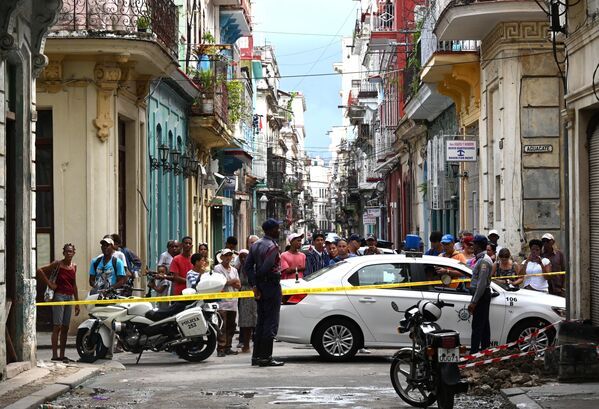 El primer derrumbe se produjo aproximadamente a las 2 de la madrugada el 4 de octubre, hora local. La gente huyó despavorida del edificio, luego de lo cual se produjo otro derrumbe.En la foto: varias personas observan cómo los equipos de rescate (fuera de cuadro) trabajan en el bloque de apartamentos luego del derrumbe.  - Sputnik Mundo