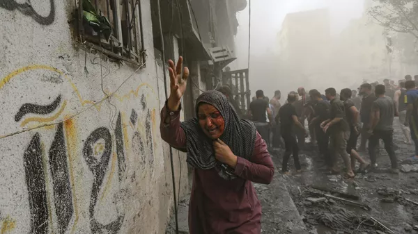 Una mujer palestina herida huye de los ataques aéreos israelíes sobre la ciudad de Gaza - Sputnik Mundo