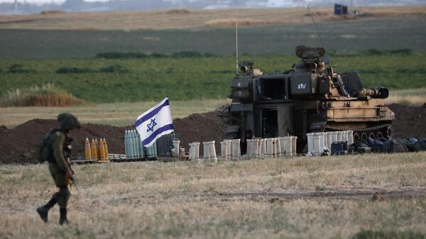 Un soldado israelí camina junto a un obús autopropulsado de 155 mm y otras municiones, en una posición del Ejército en la Franja de Gaza.  - Sputnik Mundo