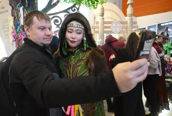 Un visitante tomándose una foto con una participante en un traje tradicional de los pueblos indígenas del Norte. Un visitante tomándose una foto con una participante en un traje tradicional de los pueblos indígenas del Norte. - Sputnik Mundo