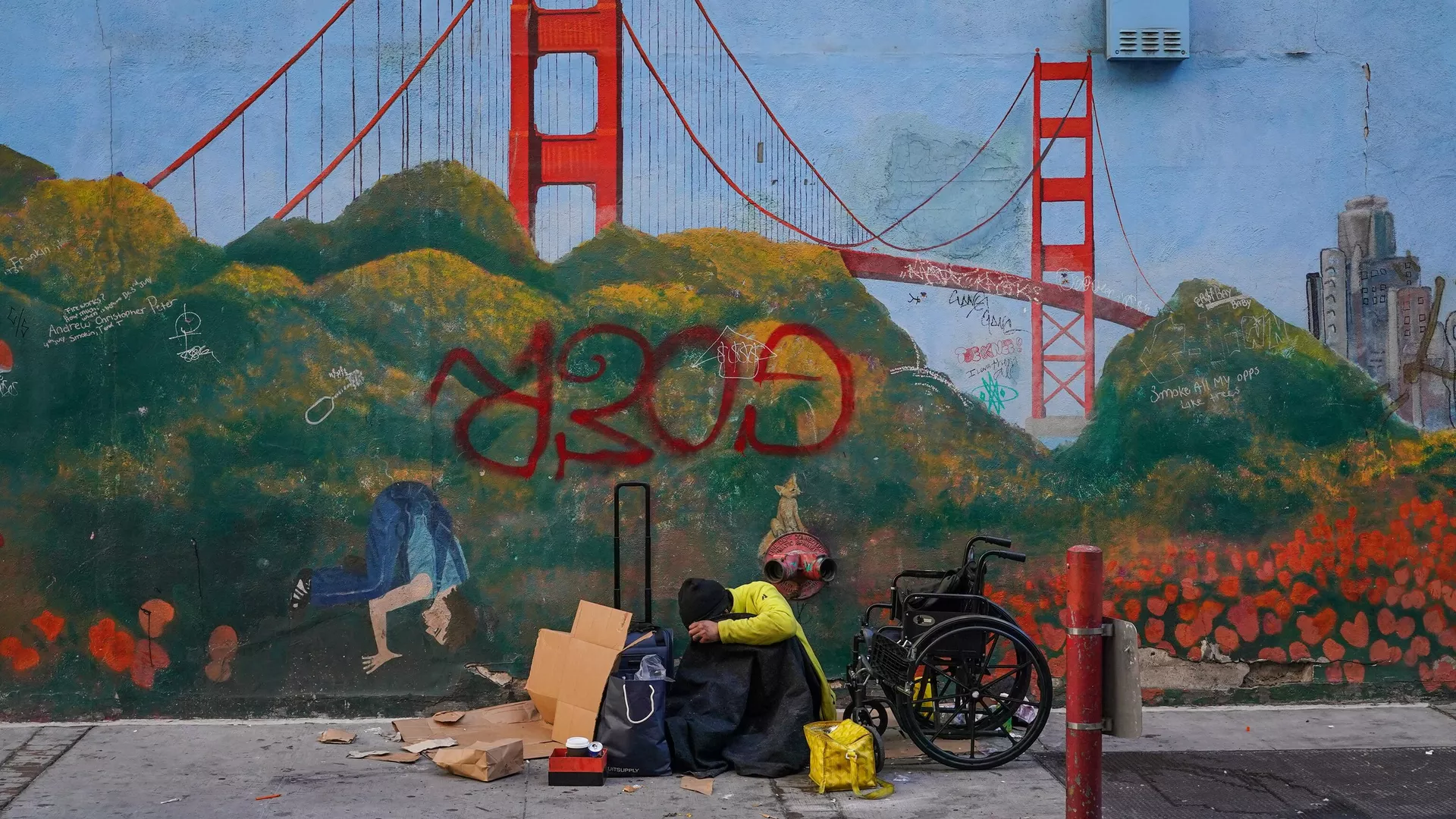 Una persona sin hogar descansa sobre un mural del puente Golden Gate cerca de la sede de la Cumbre de la APEC el 11 de noviembre de 2023 en el centro de San Francisco, California.