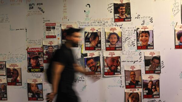 Un hombre camina junto a los retratos de rehenes israelíes pegados en una pared en Tel Aviv el 21 de noviembre de 2023, exigiendo la liberación de los israelíes retenidos como rehenes en Gaza desde el ataque del 7 de octubre - Sputnik Mundo