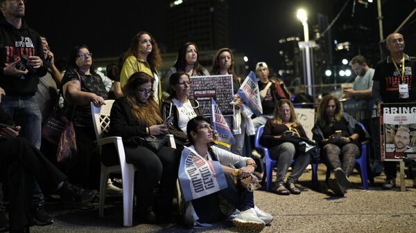 Varias personas observan en una pantalla gigante la esperada liberación de un segundo grupo de rehenes retenidos en la Franja de Gaza. - Sputnik Mundo