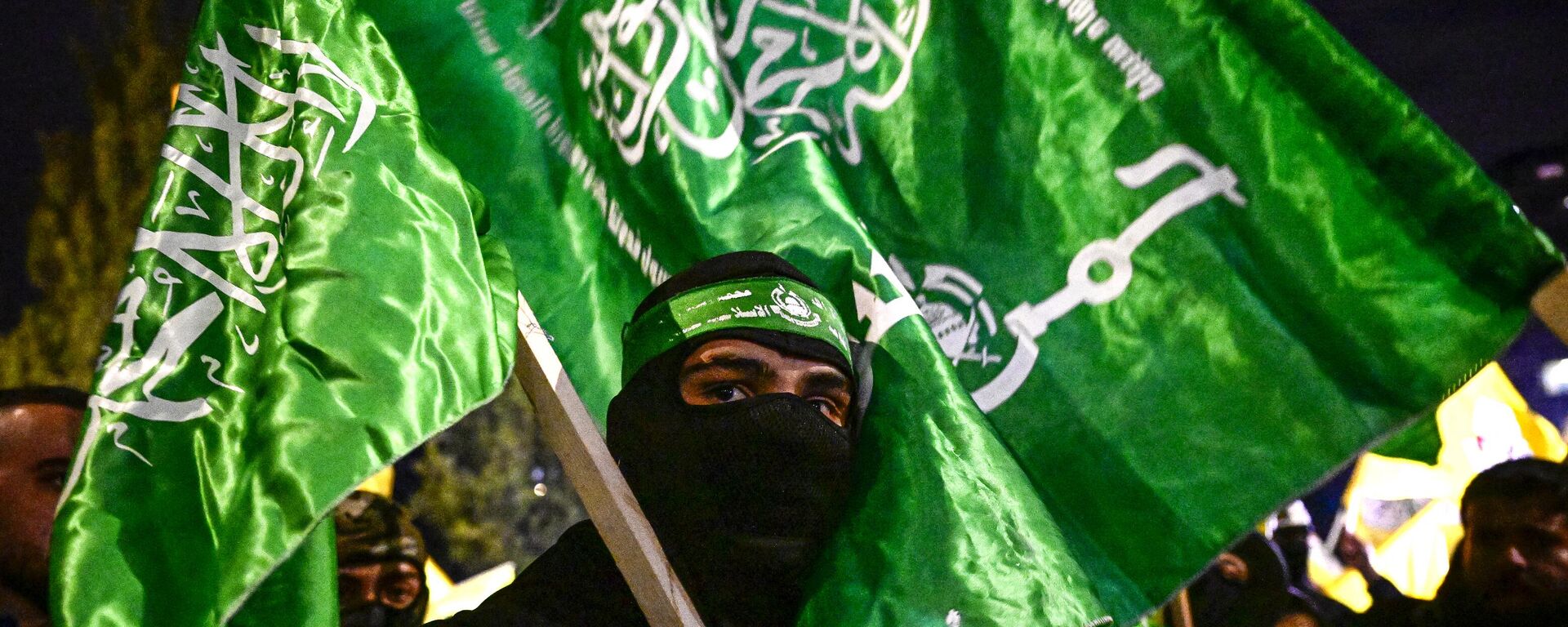 Un palestino sostiene banderas de Hamás mientras espera la liberación de prisioneros a cambio de rehenes israelíes retenidos por Hamás, en Ramala, en la Cisjordania ocupada, el 27 de noviembre de 2023  - Sputnik Mundo, 1920, 30.11.2023