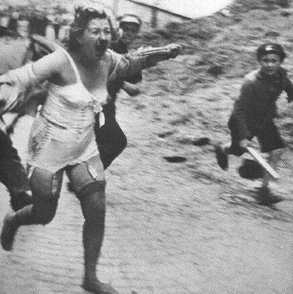 Una mujer judía perseguida por hombres y jóvenes durante el pogromo de Leópolis en julio de 1941 - Sputnik Mundo