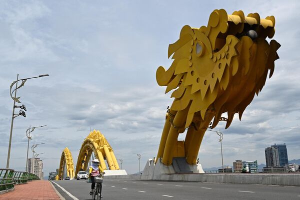 Una mujer monta en bicicleta en el Puente del Dragón en la ciudad de Danang, Vietnam. - Sputnik Mundo
