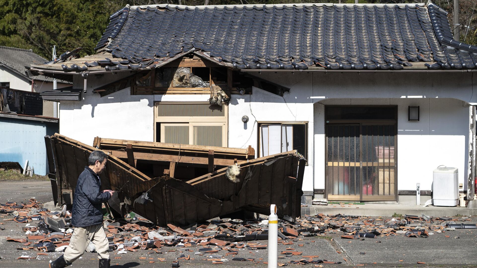 Hombre camina delante de su restaurante dañado en Shiroishi, prefectura de Miyagi, el 17 de marzo de 2022, después de que un terremoto de magnitud 7,3 sacudiera el este de Japón la noche anterior  - Sputnik Mundo, 1920, 01.01.2024