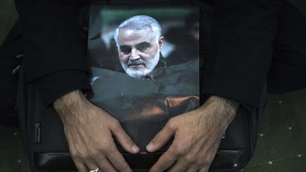 Un doliente sostiene un cartel del difunto general de la Guardia Revolucionaria, Qassem Soleimani - Sputnik Mundo