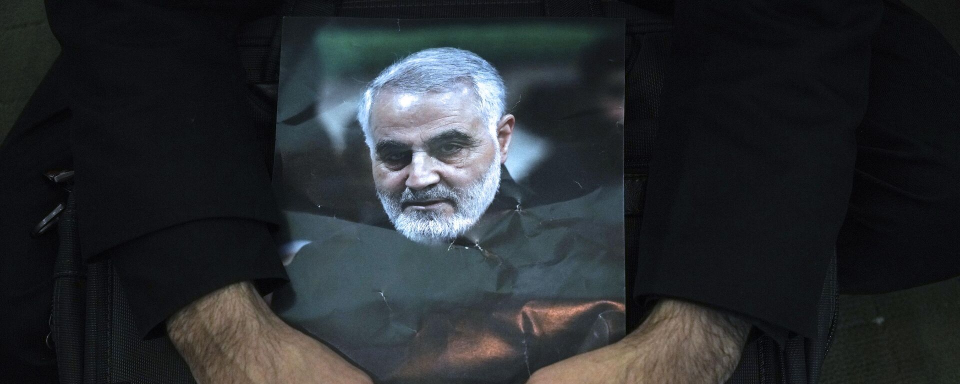 Un doliente sostiene un cartel del difunto general de la Guardia Revolucionaria, Qassem Soleimani - Sputnik Mundo, 1920, 03.01.2024