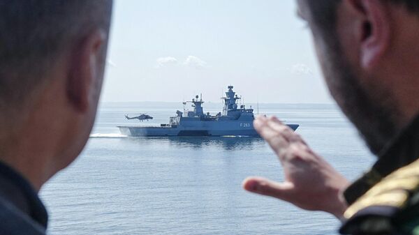 El canciller alemán Olaf Scholz habla con un militar mientras se encuentra a bordo de la fragata Mecklenburg-Vorpommern durante su visita a la Armada alemana para observar el aterrizaje de un helicóptero a bordo de la corbeta alemana Oldenburg (F263) durante unas maniobras militares en el Mar Báltico. - Sputnik Mundo