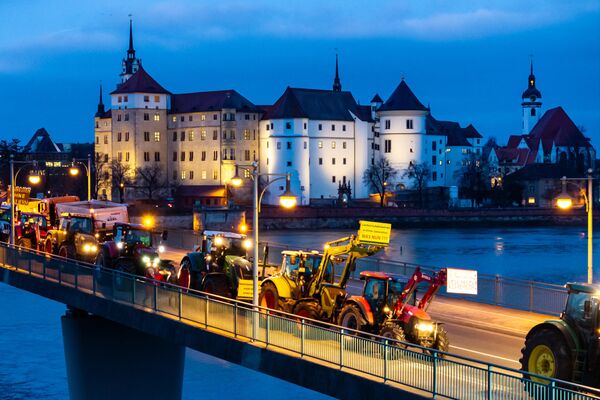 Agricultores pasando con sus tractores por delante del castillo de Hartenfels y cruzando el río Elba en Torgau, Alemania, durante una protesta contra los planes del Gobierno de suprimir las ayudas a los granjeros. Agricultores pasando con sus tractores por delante del castillo de Hartenfels y cruzando el río Elba en Torgau, Alemania, durante una protesta contra los planes del Gobierno de suprimir las ayudas a los granjeros. - Sputnik Mundo