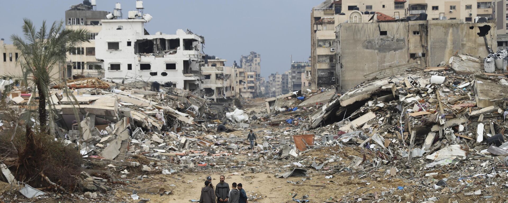 Palestinos caminan junto al edificio destruido en el bombardeo israelí de la Franja de Gaza - Sputnik Mundo, 1920, 23.01.2024