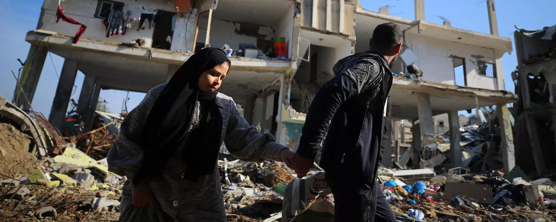 Palestinos caminan junto a un edificio destruido en el campo de refugiados de al-Maghazi, en el centro de la Franja de Gaza Palestinos caminan junto a un edificio destruido en el campo de refugiados de al-Maghazi, en el centro de la Franja de Gaza - Sputnik Mundo, 1920, 20.01.2024