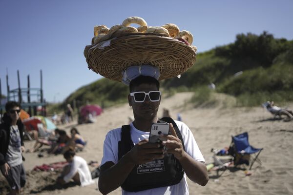 Algunas playas están muy acondicionadas, mientras que otras ofrecen un ambiente de tranquilidad y aislamiento. La gente viene aquí a disfrutar de unas cómodas vacaciones en la costa atlántica, practicando surf, wakeboard o pesca marítima.En la foto: un vendedor en la playa de Las Toninas, Argentina. - Sputnik Mundo