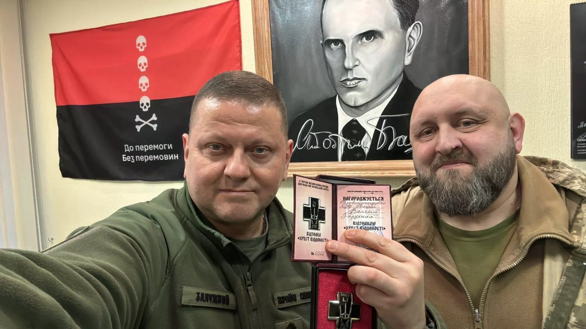 El ex comandante en jefe ucraniano, Valeri Zaluzhni, con el comandante de la 67.ª Brigada Mecanizada ucraniana, Andriy Stempitski, posan delante de un retrato de Stepan Bandera