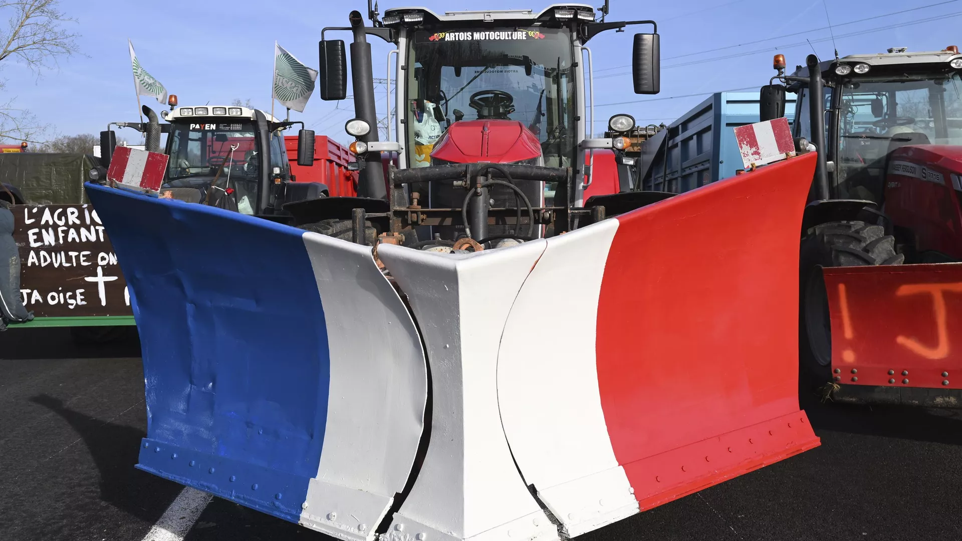 Tractores, el del centro con los colores de la bandera francesa, bloquean una carretera el 29 de enero de 2024 al norte de París