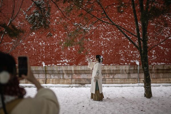 Una mujer con traje tradicional posa para una foto un día después de una nevada en Pekín, China. Una mujer con traje tradicional posa para una foto un día después de una nevada en Pekín, China. - Sputnik Mundo